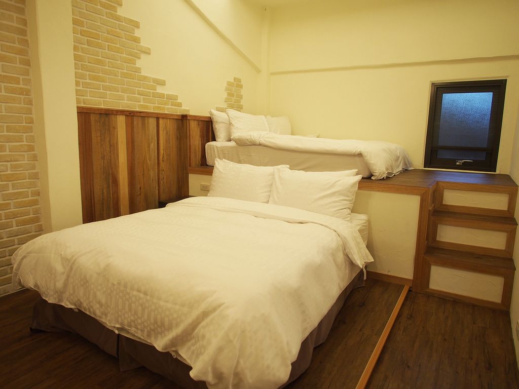 Un dormitorio con una cama, un televisor y un escritorio de madera.
