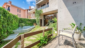 Ein modernes Gebäude mit Balkon, Holzlattenzaun und einer Topfpflanze.