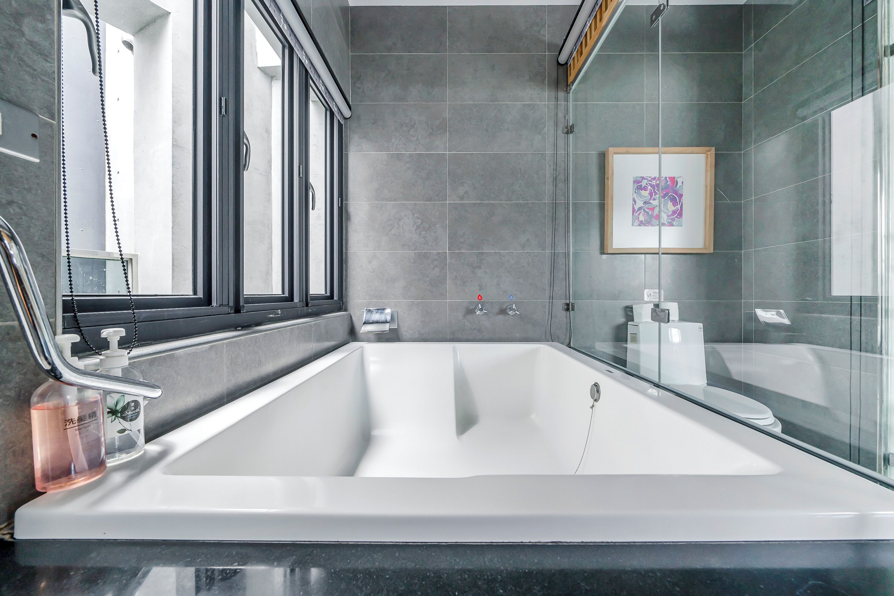 Une salle de bain moderne avec une grande baignoire, une douche en verre et une œuvre d’art encadrée au mur.