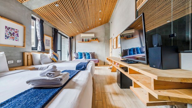 Ein modernes Hotelzimmer mit einem großen Bett, einem Holztisch, einem Flachbildfernseher und Kunstwerken an den Wänden.