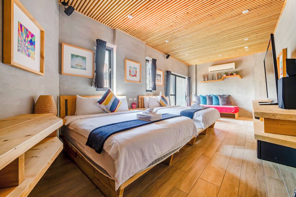 A modern hotel room with two beds, wooden furniture, and framed artwork on the walls.