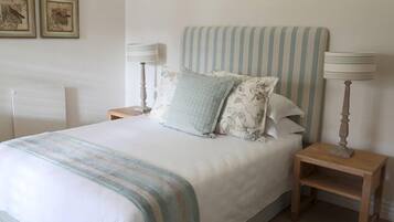 A neatly made bed with striped bedding, two bedside lamps, and two framed pictures on the wall.