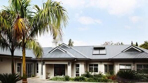 A two-story house with a grey roof, a front porch, and a landscaped garden. - Kingsmead Guest House (Harare)