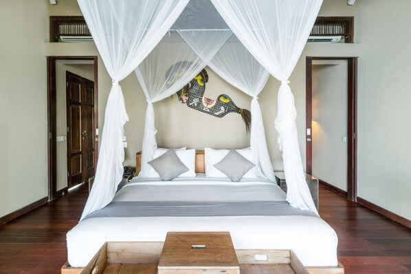 A spacious bedroom with a large bed, white canopy, and a decorative wall piece. - Villa Melissa (Munggu)