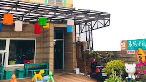 A colorful building with multiple balconies, a covered entrance, and outdoor seating. - Warner Leisure Hotel (Hengchun)