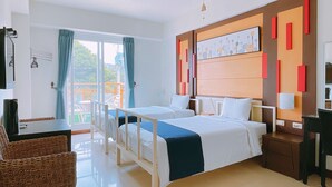 A hotel room with two beds, a desk, a chair, and a view of the outdoors. - Warner Leisure Hotel (Hengchun)