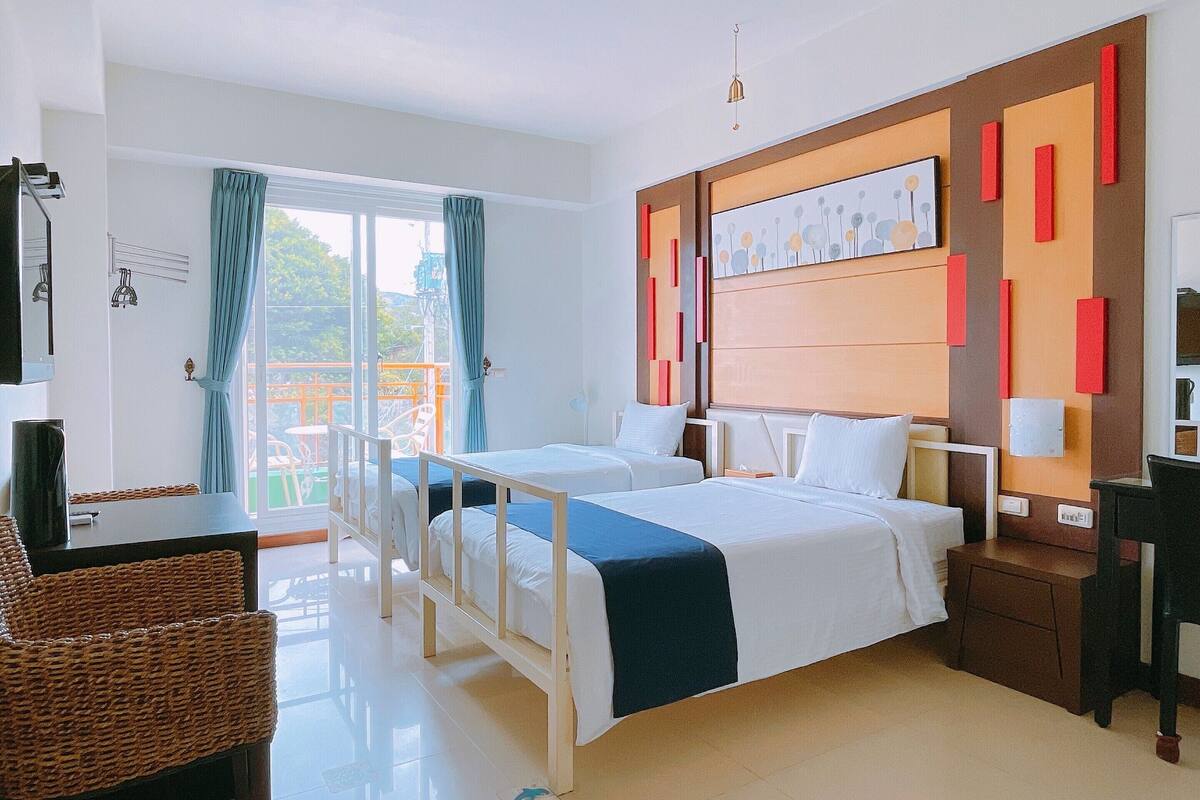 Ein Hotelzimmer mit zwei Betten, einem Schreibtisch, einem Stuhl und Blick ins Freie.