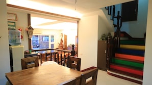 A dining area with a wooden table and chairs, a water dispenser, and a staircase with colorful steps. - Warner Leisure Hotel (Hengchun)