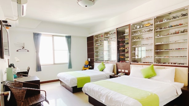 A hotel room with two beds, a large shoe display, a desk, and a window with curtains. - Warner Leisure Hotel (Hengchun)