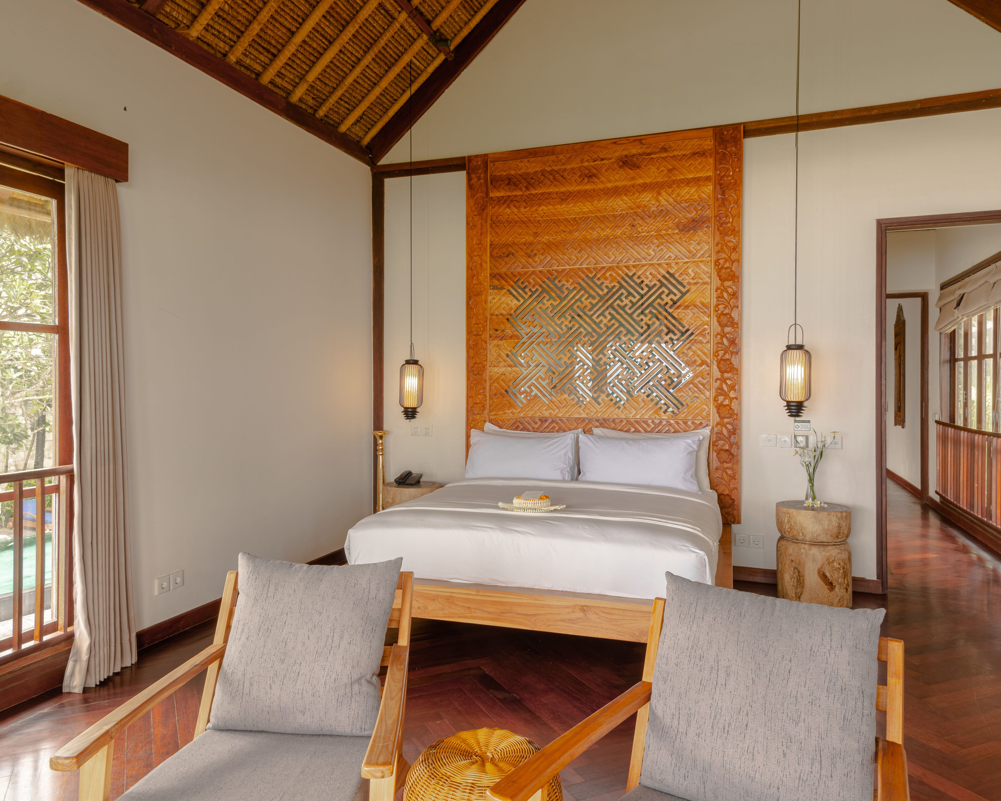 Un dormitorio con una cama grande, dos mesitas de noche, un cabecero de madera y vistas al exterior a través de una ventana.