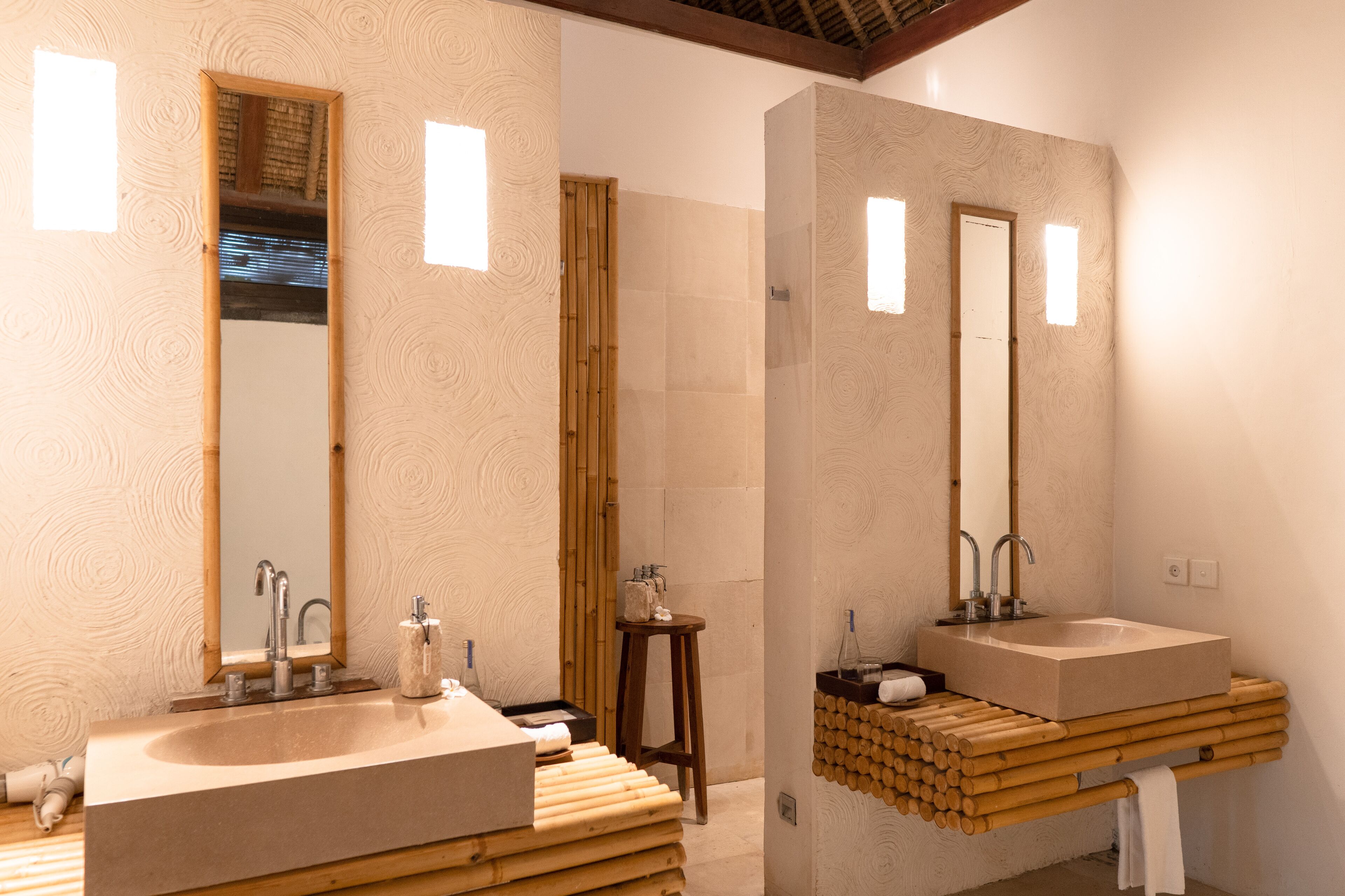 A modern bathroom with two sinks, large mirrors, and a wooden stool.