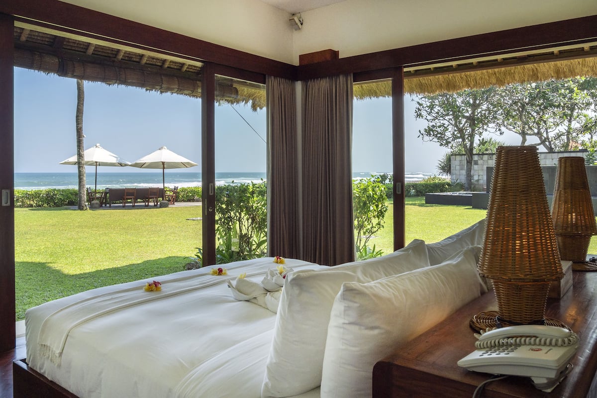 A bedroom with a large bed, a telephone, and a view of the ocean.