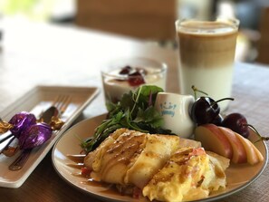 Savor a delicious meal at this casual dining setting, featuring a warm pastry, fresh greens, and a side of fruit compote.
