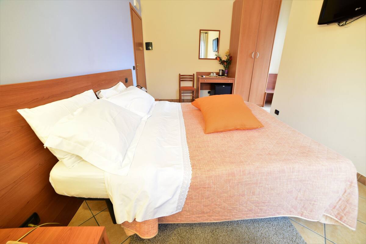 Una habitación de hotel con cama, escritorio, silla y televisor.
