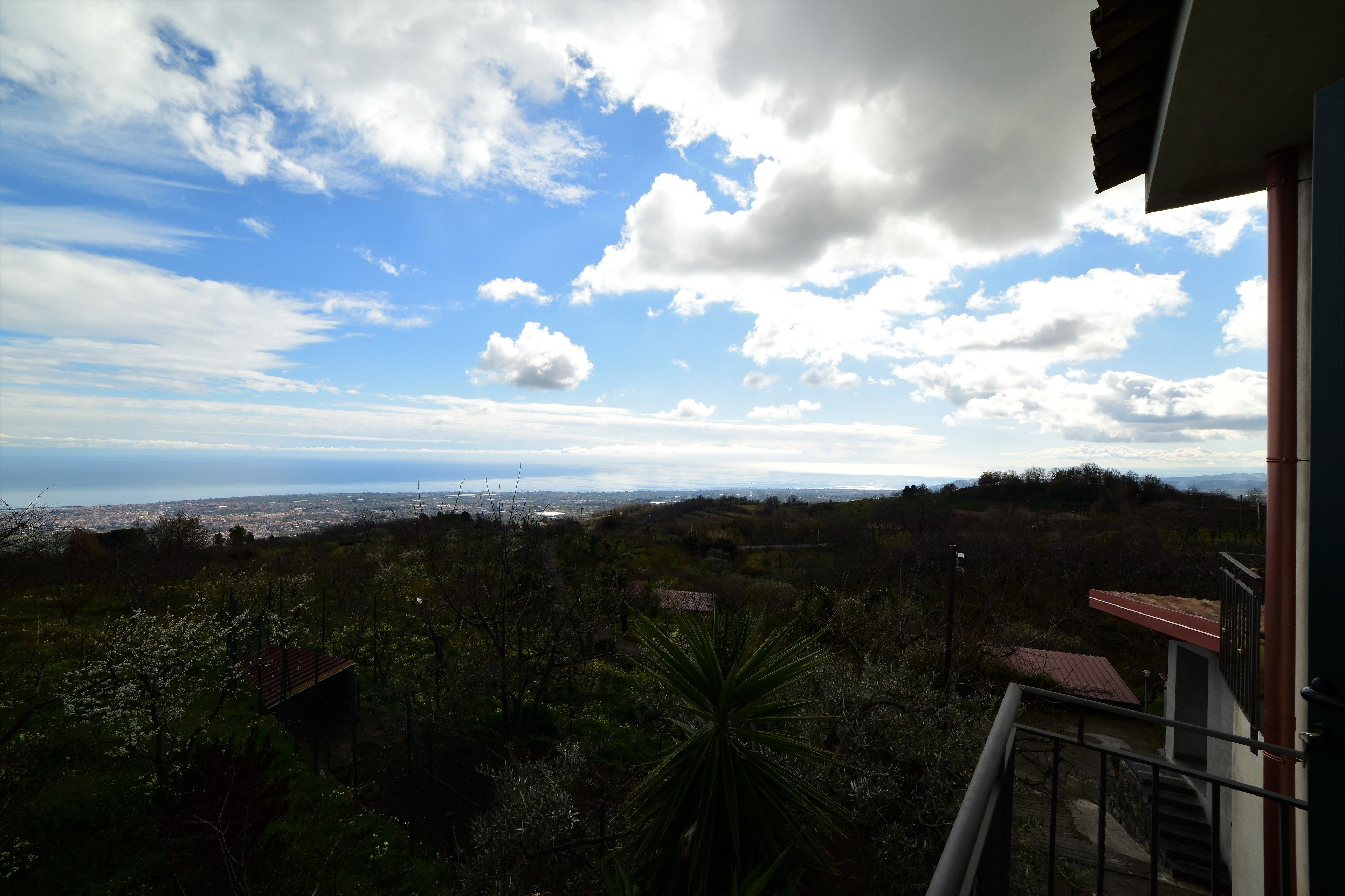 A balcony with a view of a cityscape and distant mountains.