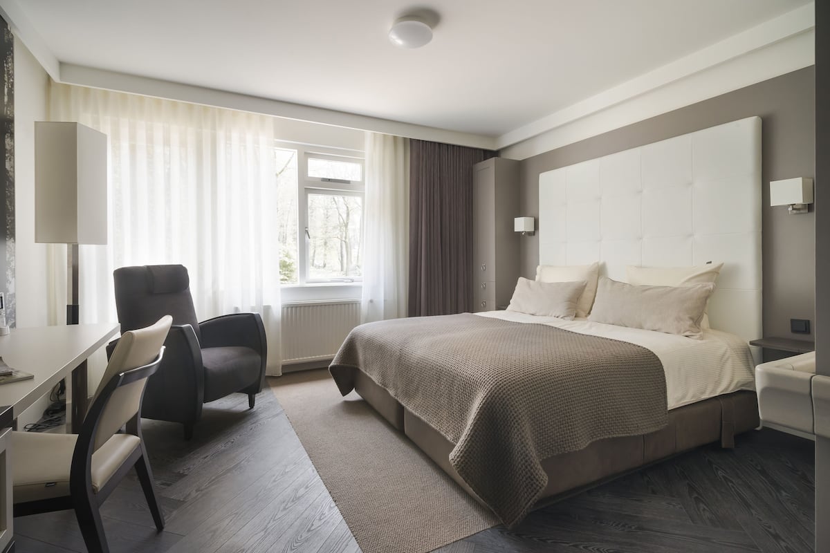 Una habitación de hotel moderna con una cama grande, un escritorio y una silla.