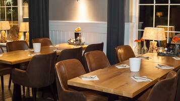 Un espace repas comprenant plusieurs tables en bois et des chaises en cuir, agrémenté de lampes de table et de vases décoratifs.