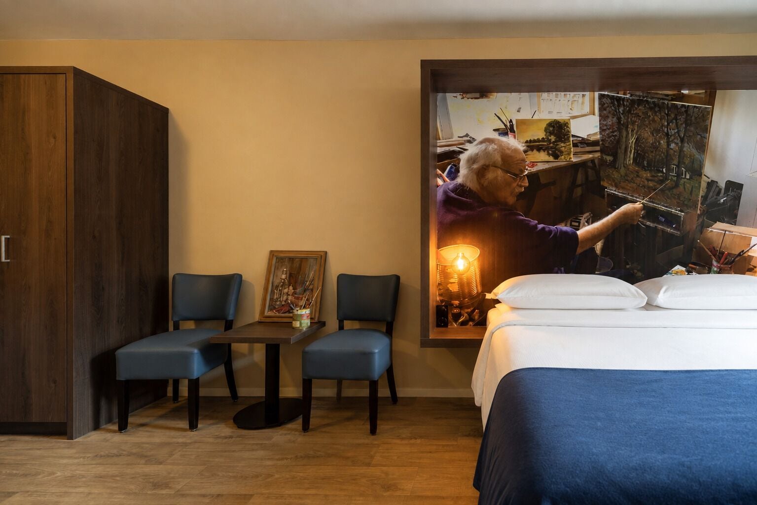 Ein Hotelzimmer mit einem Bett, zwei Stühlen, einem Tisch und einem Kleiderschrank.