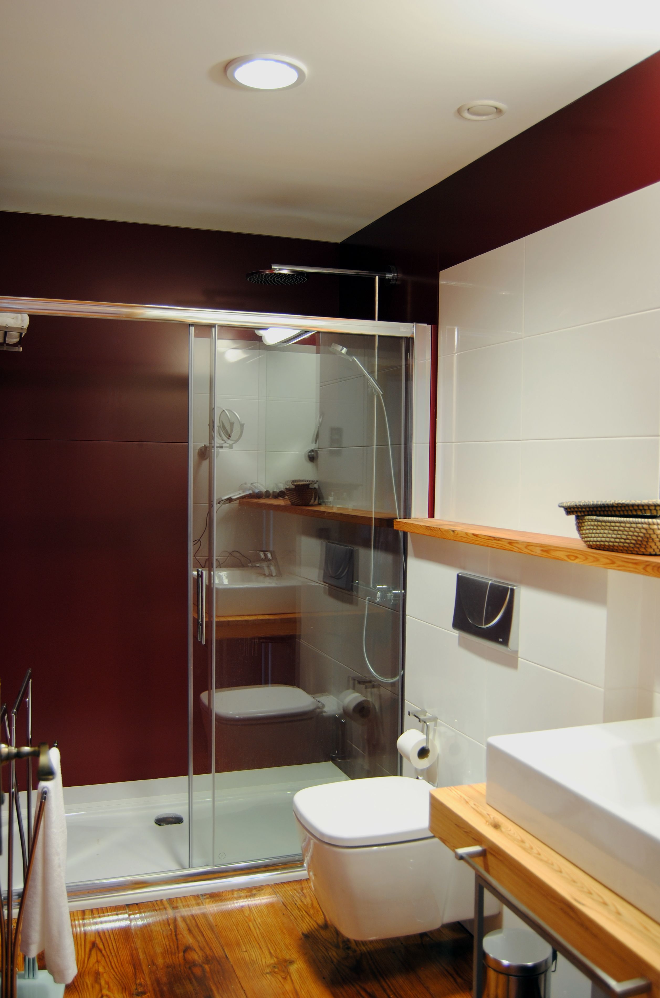 Ein modernes Badezimmer mit Duschkabine aus Glas, einer weißen Toilette und einem Holzwaschtisch mit Korb.