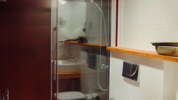 Ein modernes Badezimmer mit Duschkabine aus Glas, einer weißen Toilette und einem Holzwaschtisch mit Korb.