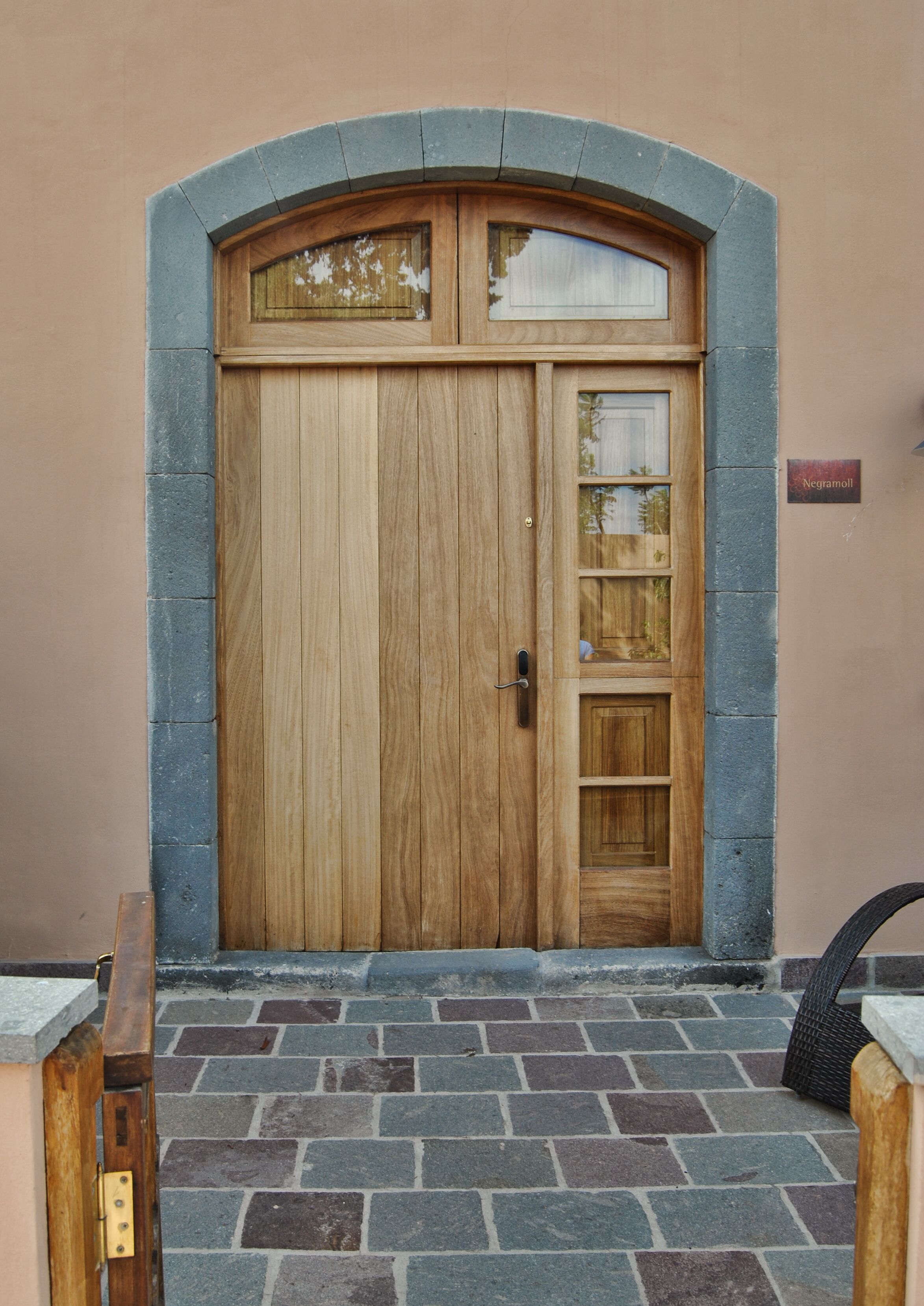 A wooden door with a glass panel and a small window above it, set in a stone archway.