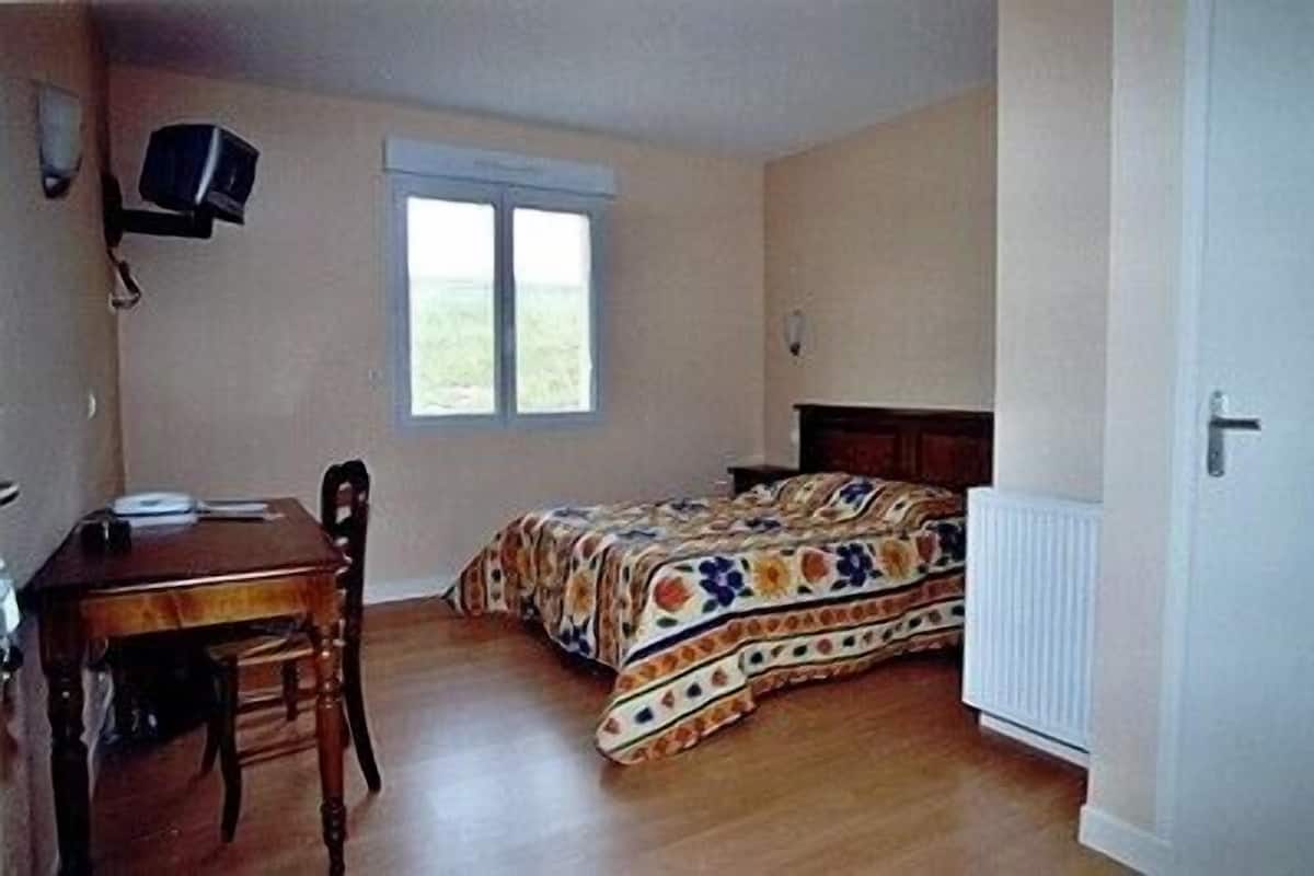 A bedroom with a bed, a desk, and a chair.