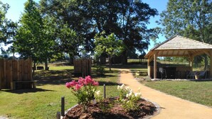 A park with a paved walkway, wooden structures, and a gazebo. - Le Domaine de Renaudet (Saint-Pantaleon-de-Larche)