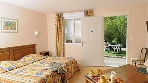 A room with two beds, a dining table with breakfast items, a window with curtains, and a view of the outdoors. - Le Domaine de Renaudet (Saint-Pantaleon-de-Larche)