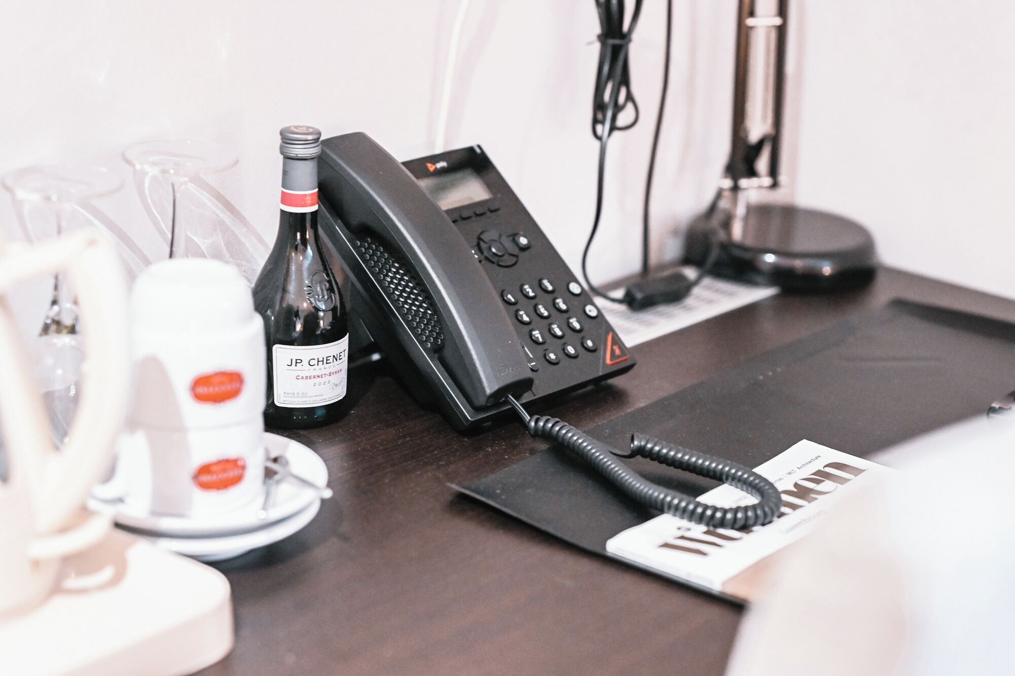 A hotel reception desk with a telephone, a wine bottle, and a menu.