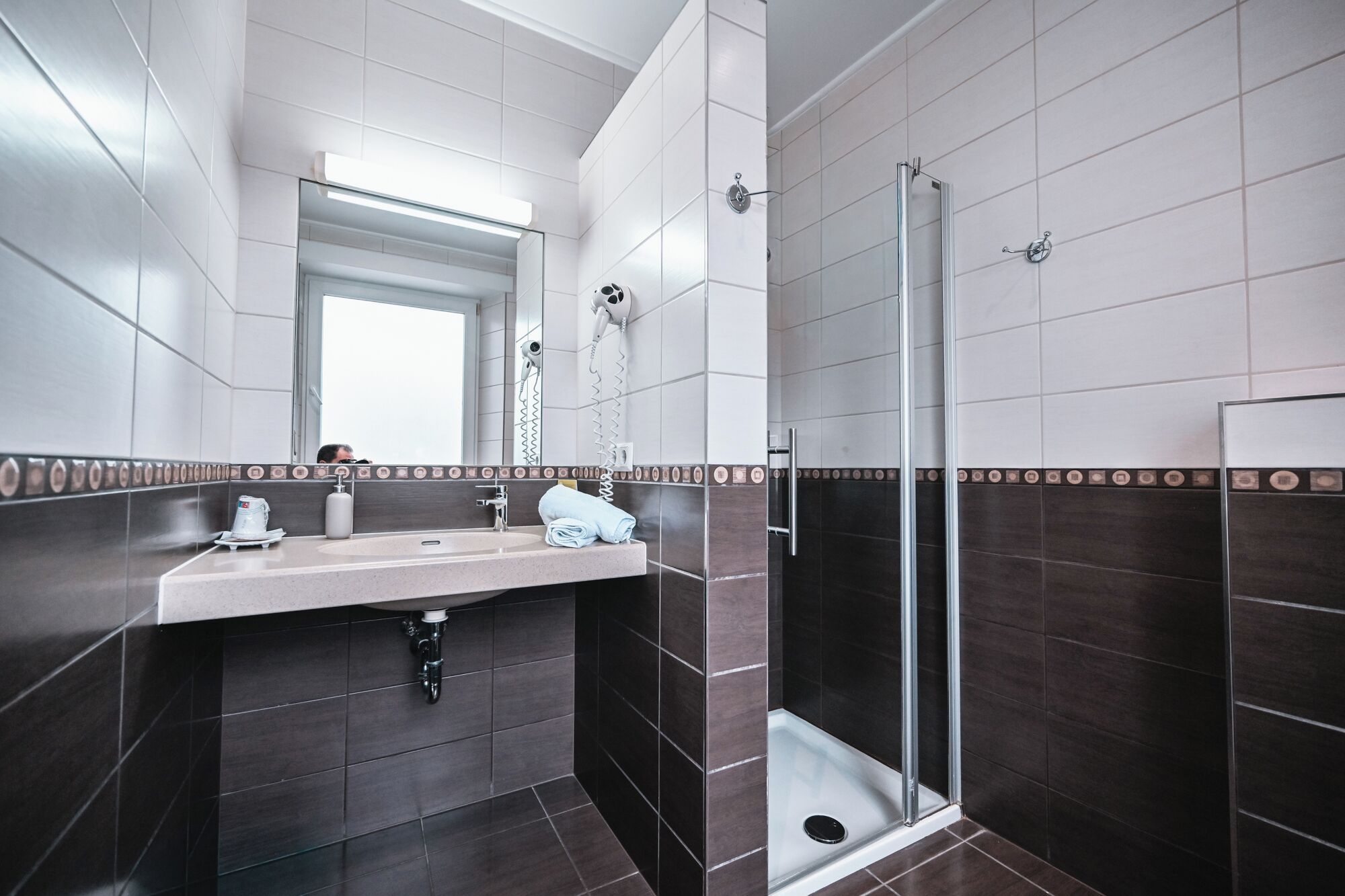 Un baño moderno con un espejo grande, un lavamanos, una toalla y una zona de ducha.