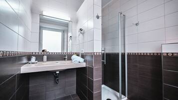 Un baño moderno con un espejo grande, un lavamanos, una toalla y una zona de ducha.