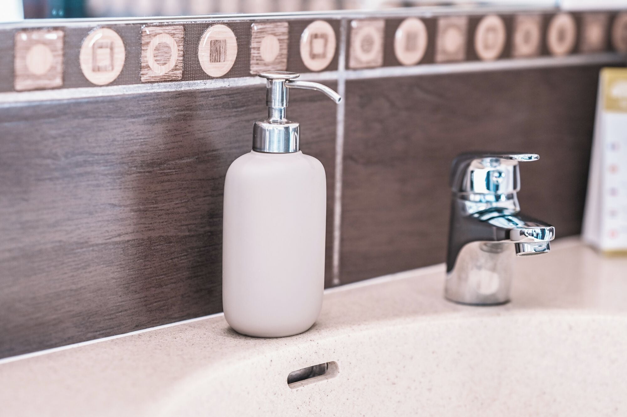 Een badkamer met een witte zeepdispenser en een chromen kraan.