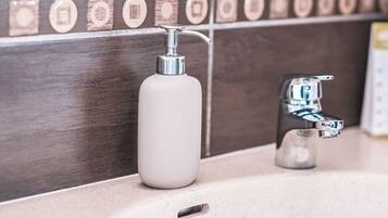 Een badkamer met een witte zeepdispenser en een chromen kraan.