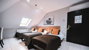 Habitació d'hotel moderna amb dos llits individuals, un fanal i un radiador blanc.