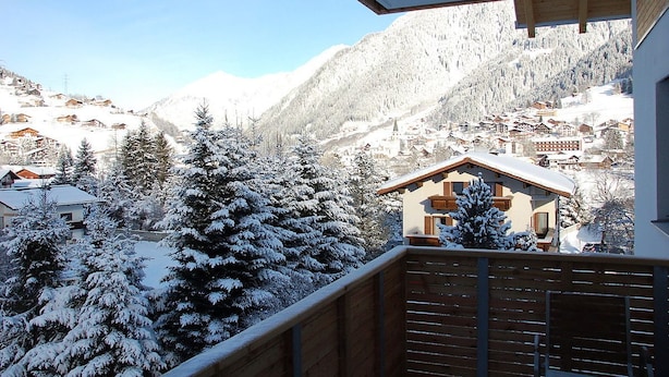 A snowy mountain village with traditional houses, a wooden balcony, and a clear view of the surrounding mountains. - Appart Laijola (Gaschurn)