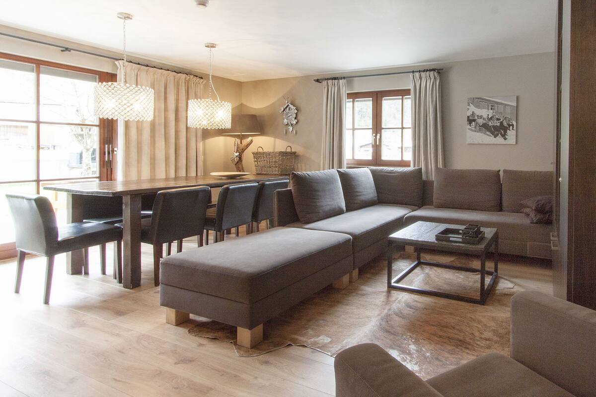 A modern living room with a sectional sofa, a dining table with chairs, and a coffee table.