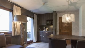 A modern kitchen with dark cabinetry, a microwave, and a dining area with a wooden table and chairs. - Appart Laijola (Gaschurn)