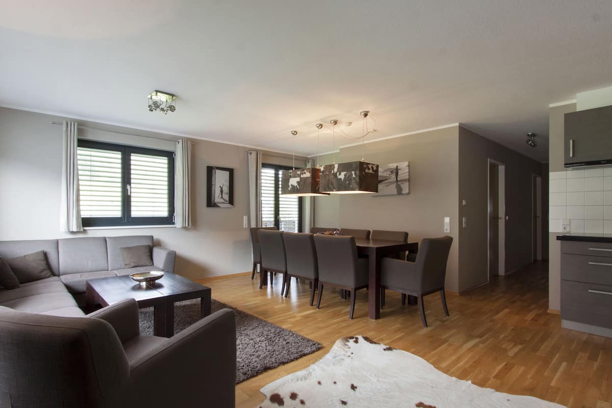 A modern living room with a sofa, coffee table, and dining area with chairs.