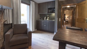 A modern kitchen with dark cabinets, a microwave, and a coffee maker. There is a dining area with a wooden table and chairs. - Appart Laijola (Gaschurn)
