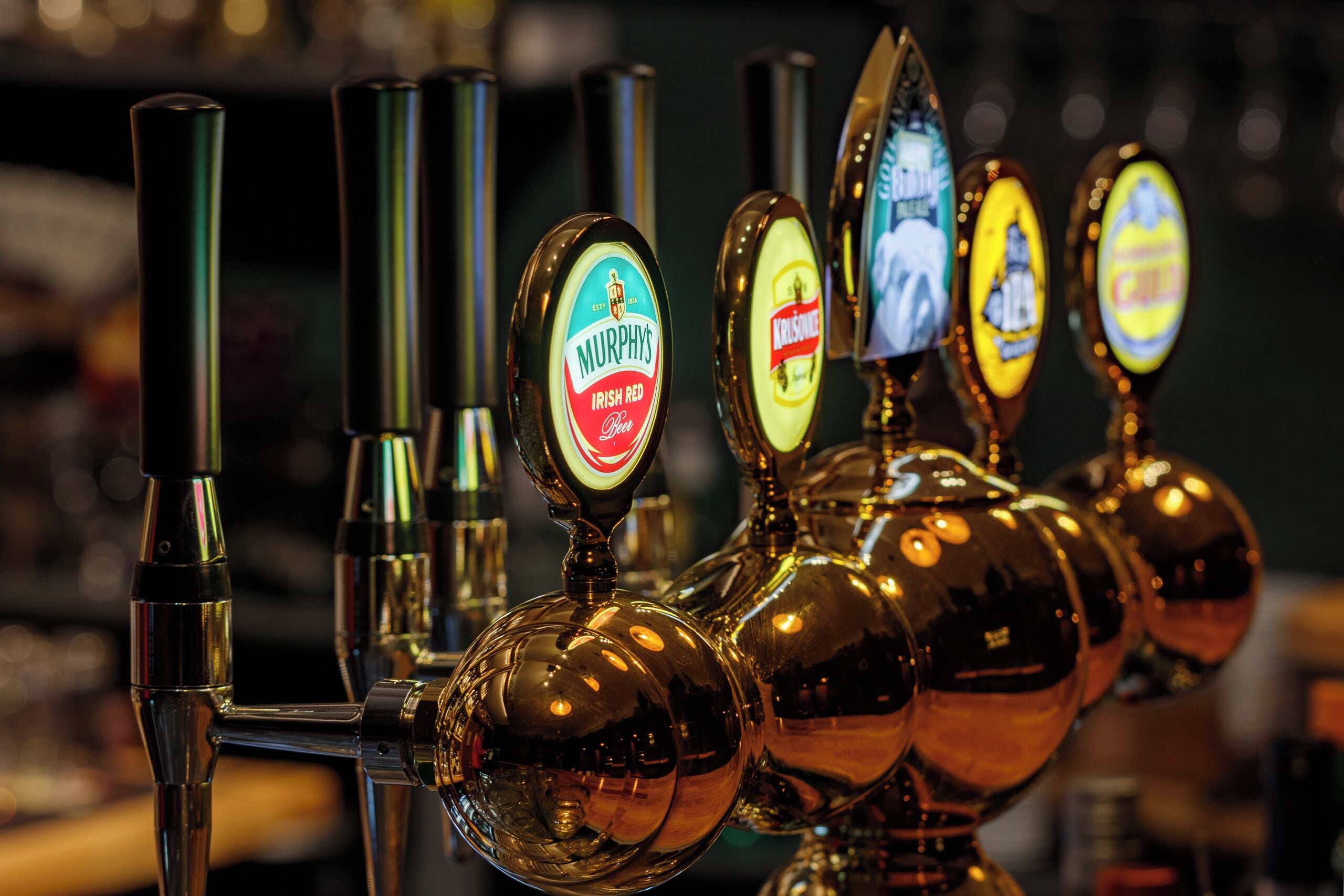 A row of beer taps with labels for Murphy's Irish Red and Krusky.