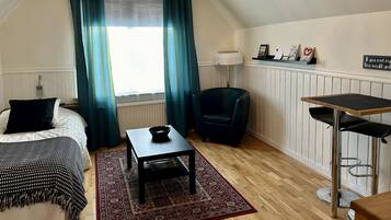 Una habitación acogedora con una cama, una mesita, una silla y un escritorio.