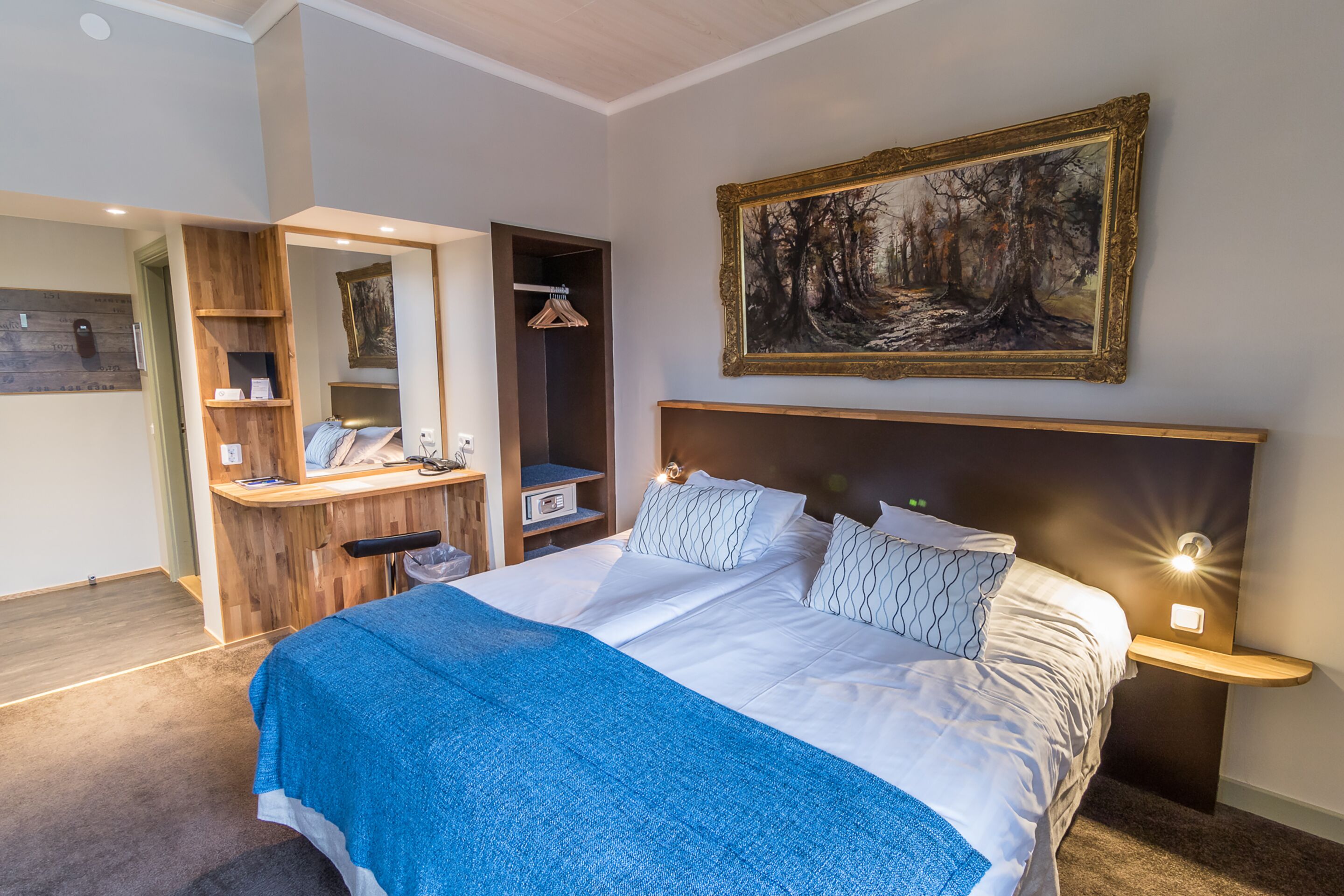 A bedroom with a large bed, a dresser, a mirror, and a painting on the wall.