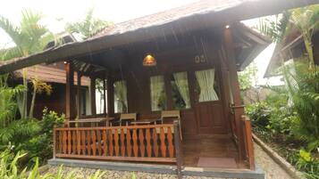 A wooden building with a porch, stone steps, and a wooden railing.