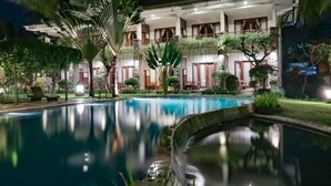 A hotel with a swimming pool, lush greenery, and a well-lit exterior. - Mina Tanjung Hotel (Tanjung)