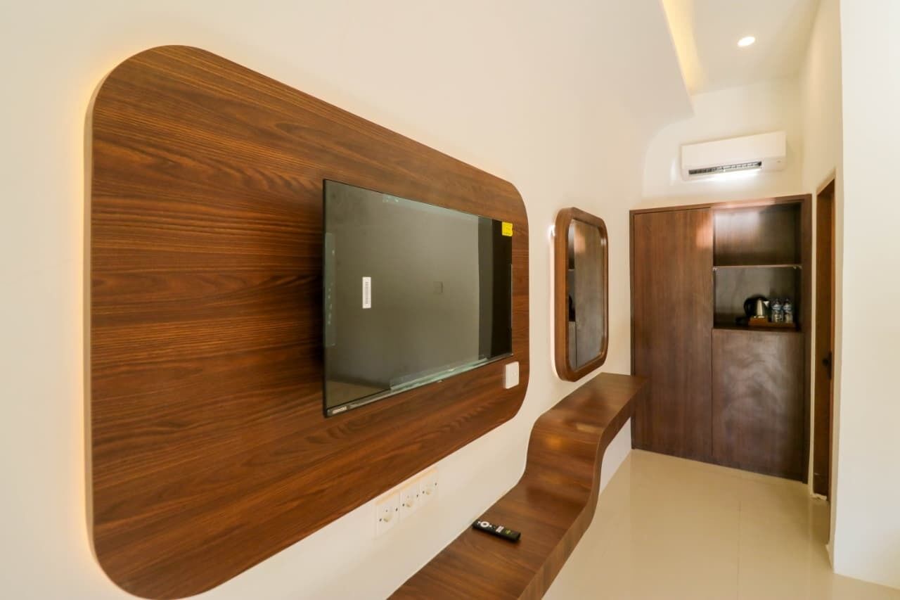 Una sala de estar moderna con un televisor de pantalla plana montado en una pared de madera, un mueble empotrado y un control remoto en el suelo.