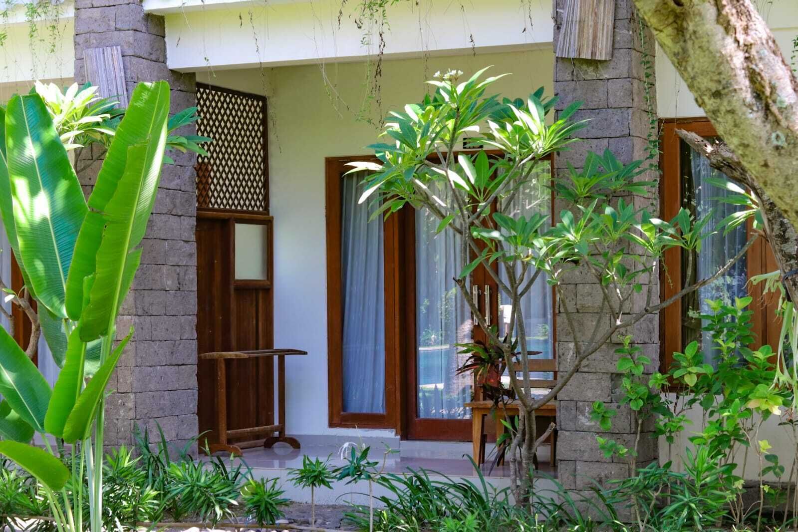 A house with a stone facade, a wooden door, and a window with a curtain.