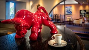 A red bull sculpture on a table with a cup of coffee. - Gilles Moreau (Laguiole)