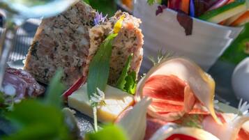 Diverse etenswaren, zoals brood, kaas en groenten, wat doet denken aan een picknick of diner in de openlucht.