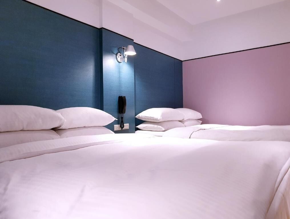 Una habitación de hotel moderna con una cama grande, una mesita de noche y una lámpara de pared.