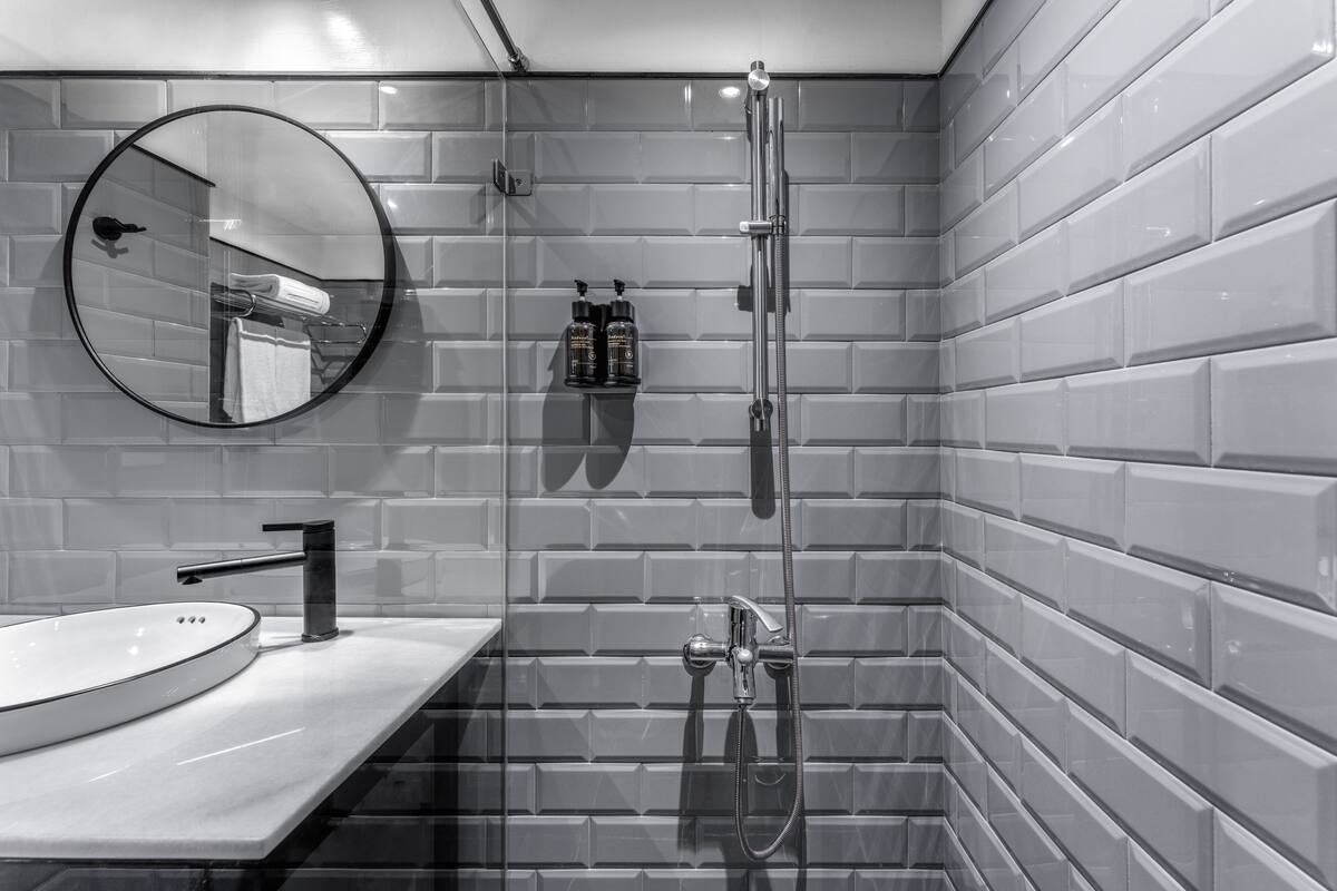 A modern bathroom with a round mirror, a sink, and a shower.